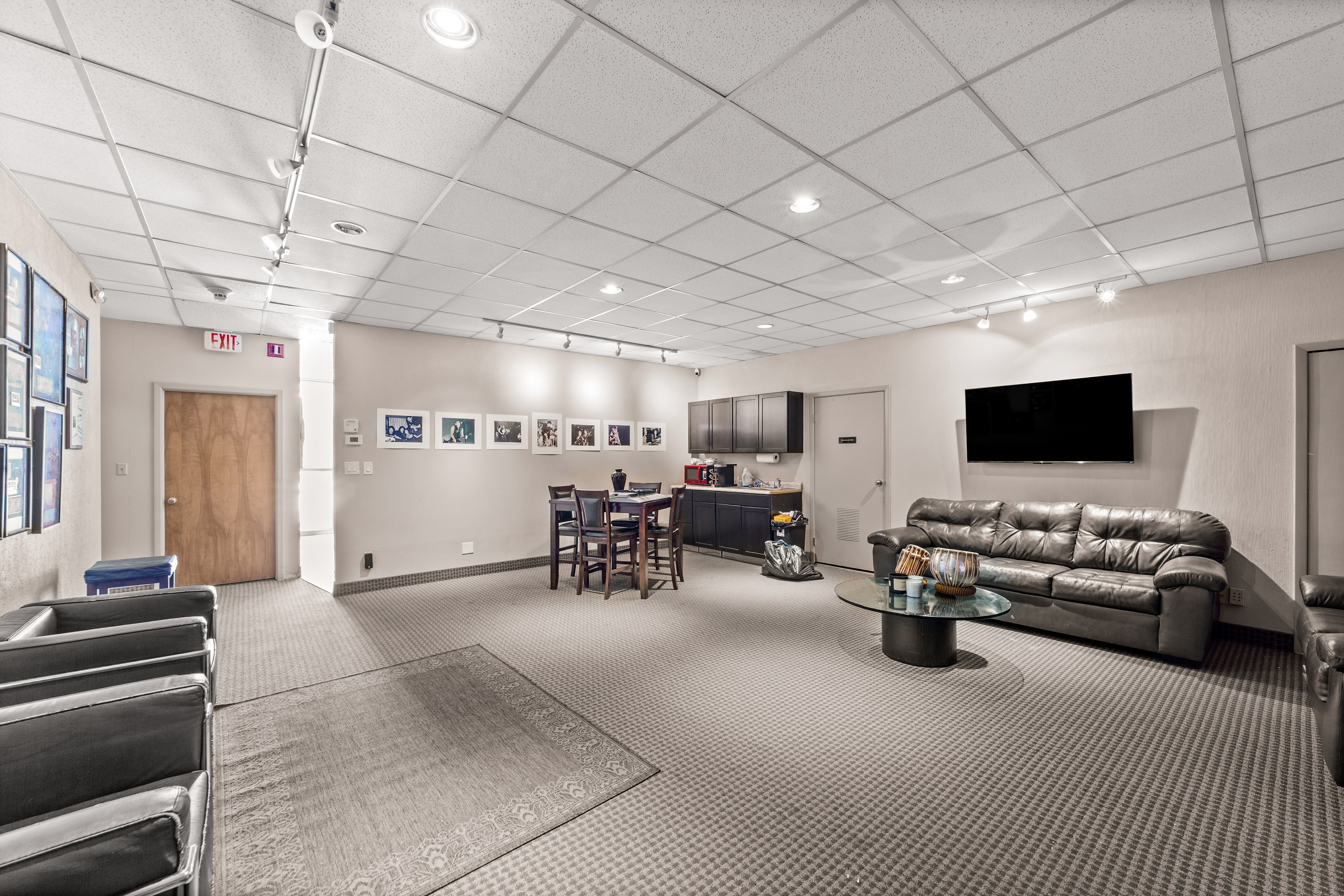 Spacious lounge area with black leather couches and kitchenette