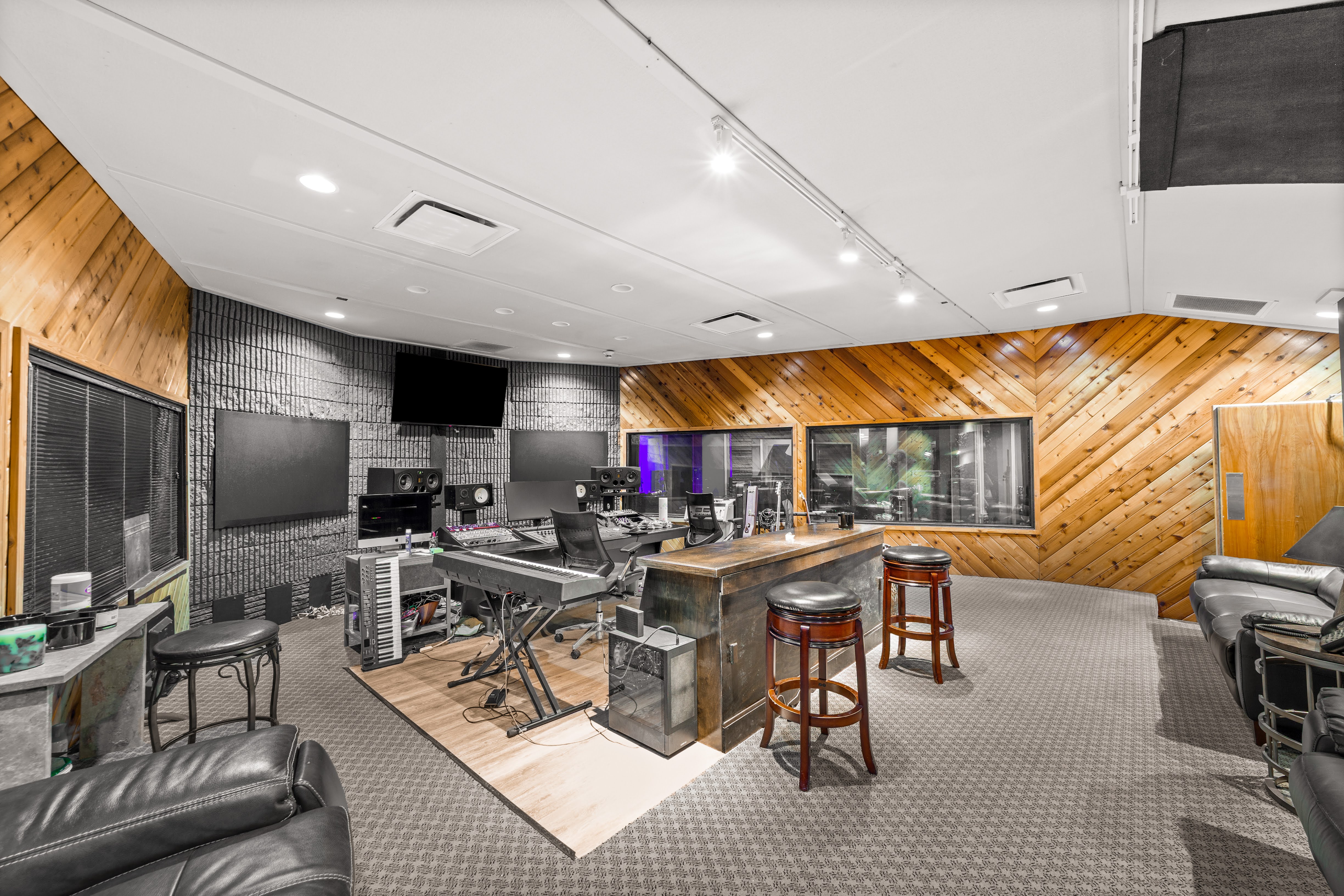 Spacious music studio control room with wood-paneled walls