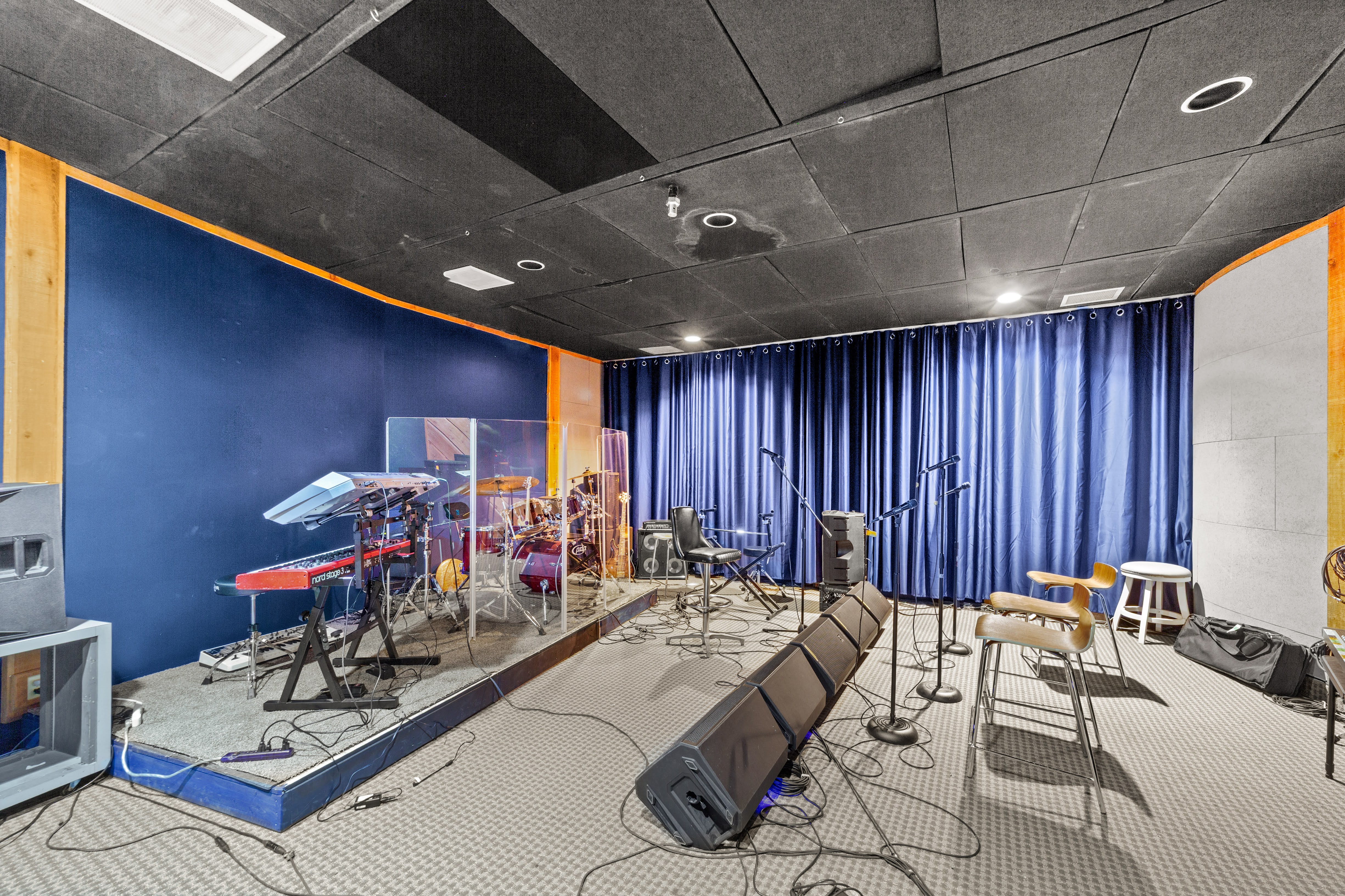 Music studio with drum kit, keyboards, and blue curtains