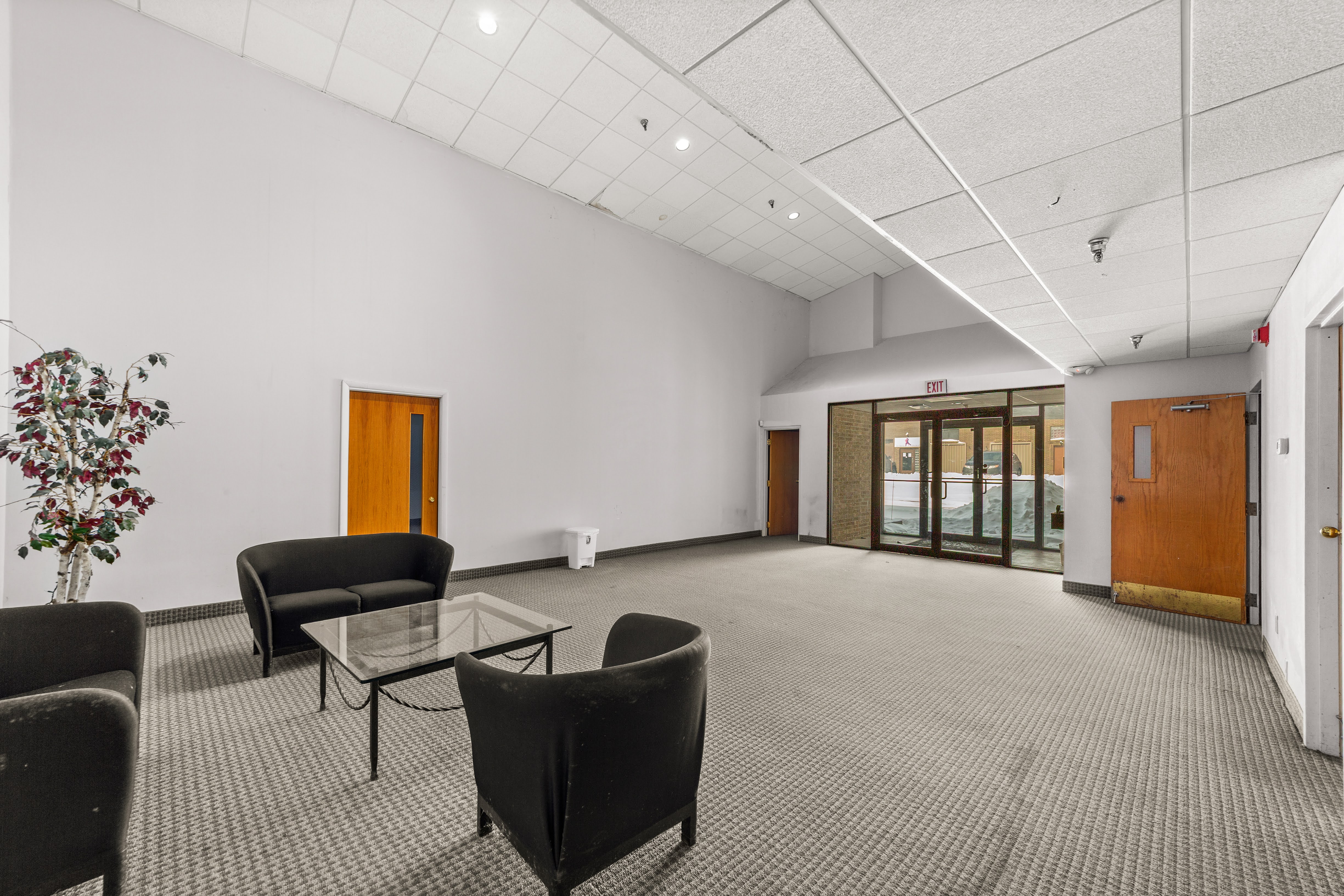 Carpeted lobby with black sofa and glass coffee table