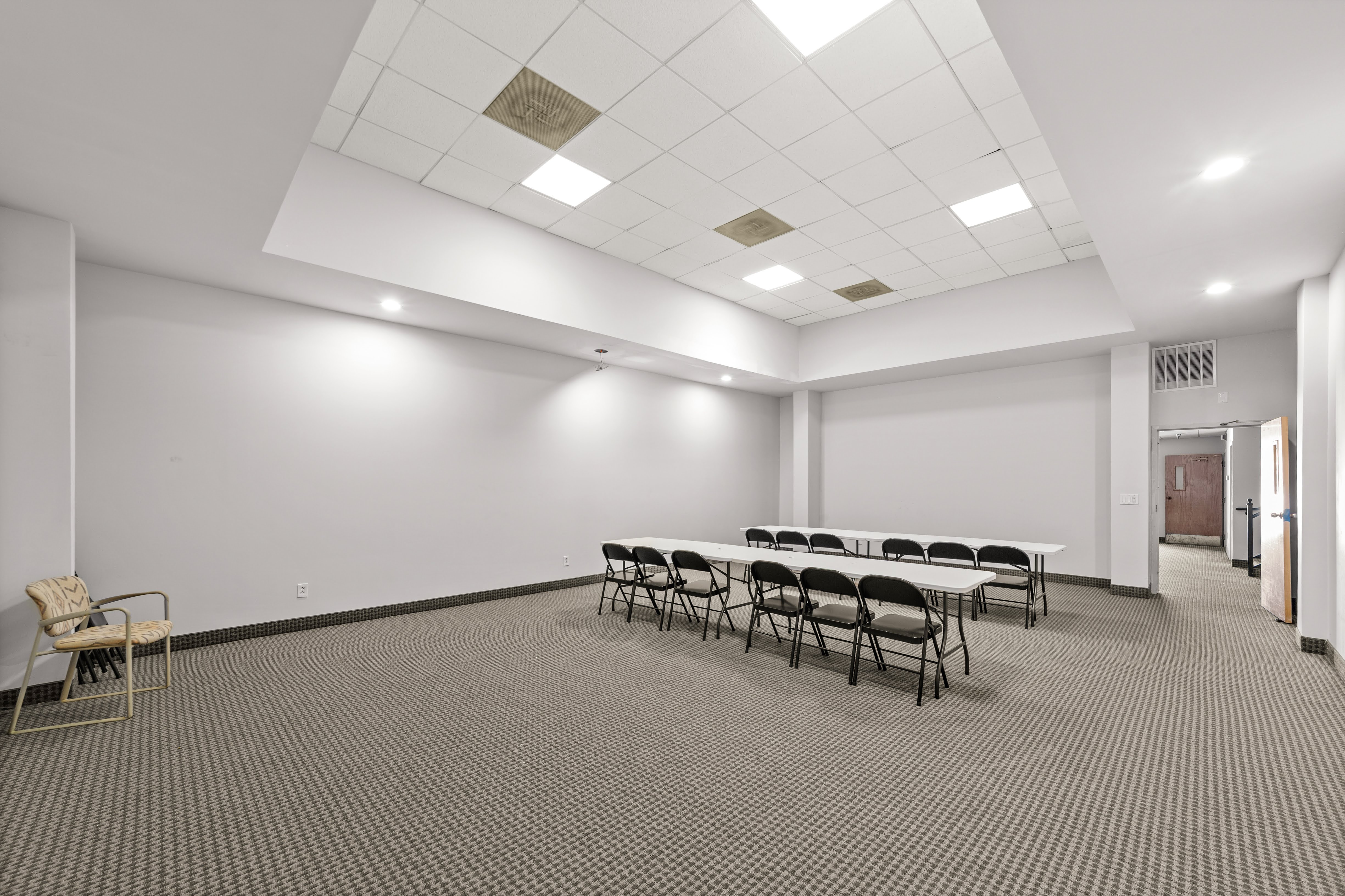 Empty meeting room with white tables and black chairs