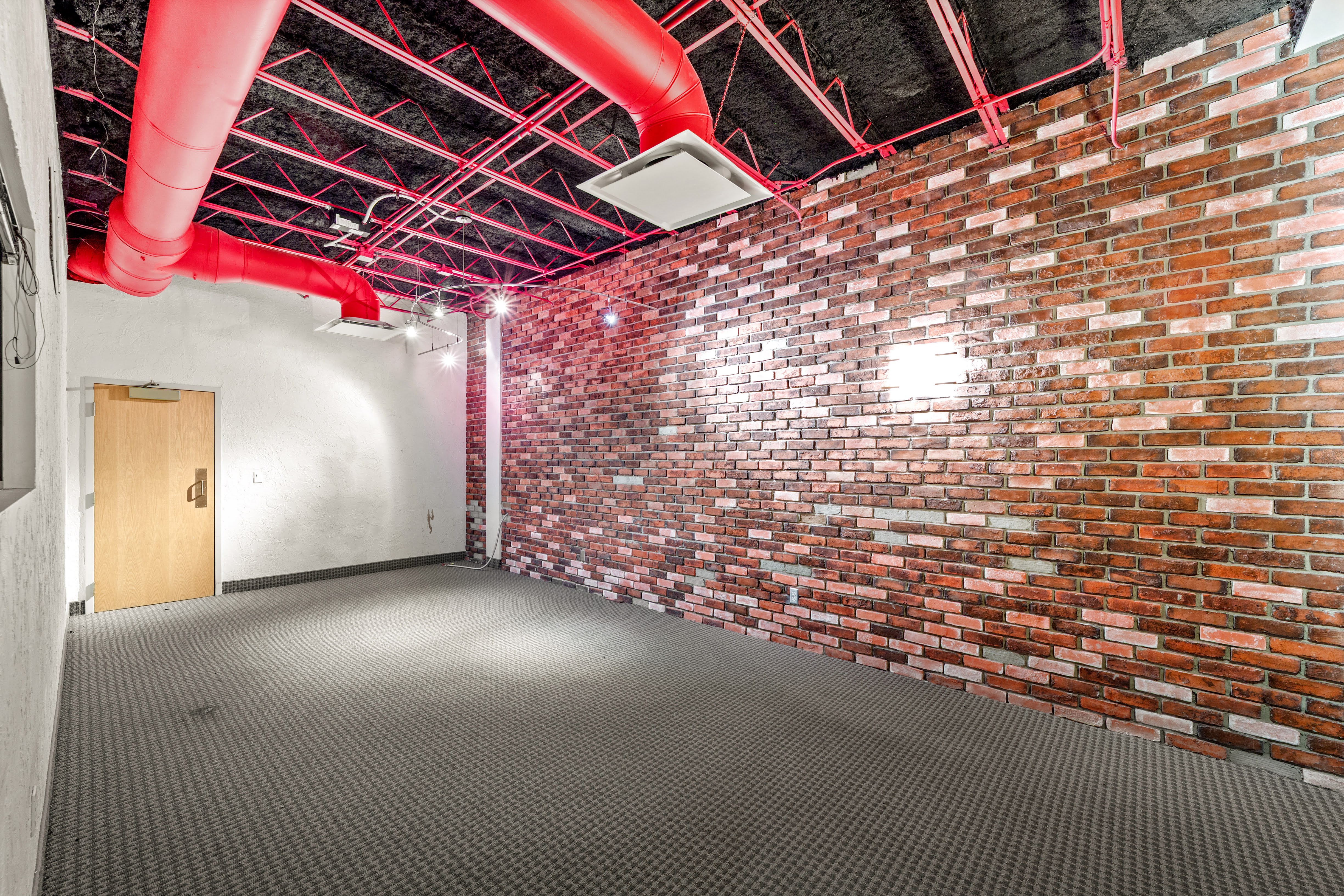 Empty commercial room with red brick wall and exposed ceiling