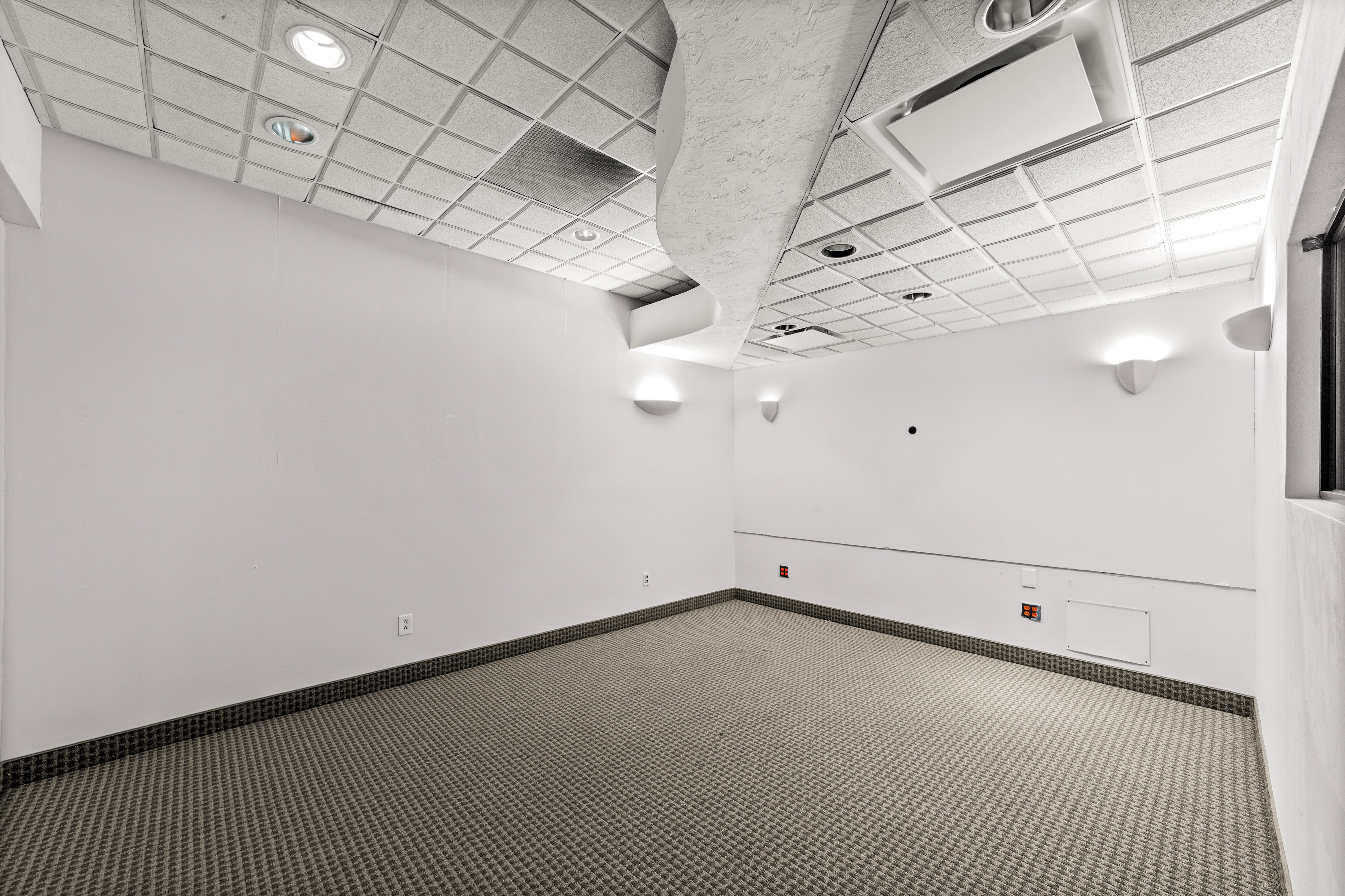 Empty neutral-toned commercial room with wall sconces
