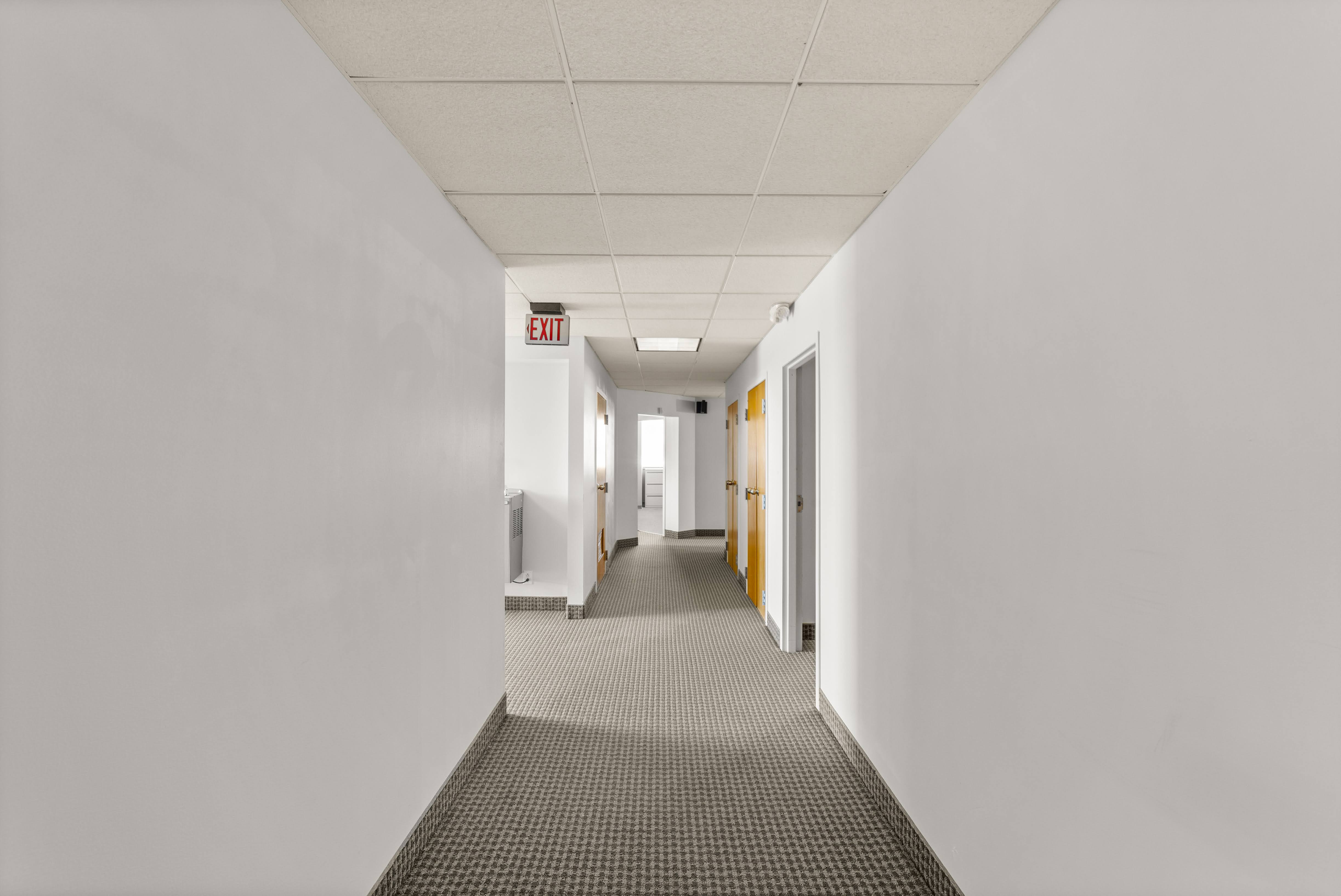 Empty office hallway with red EXIT sign