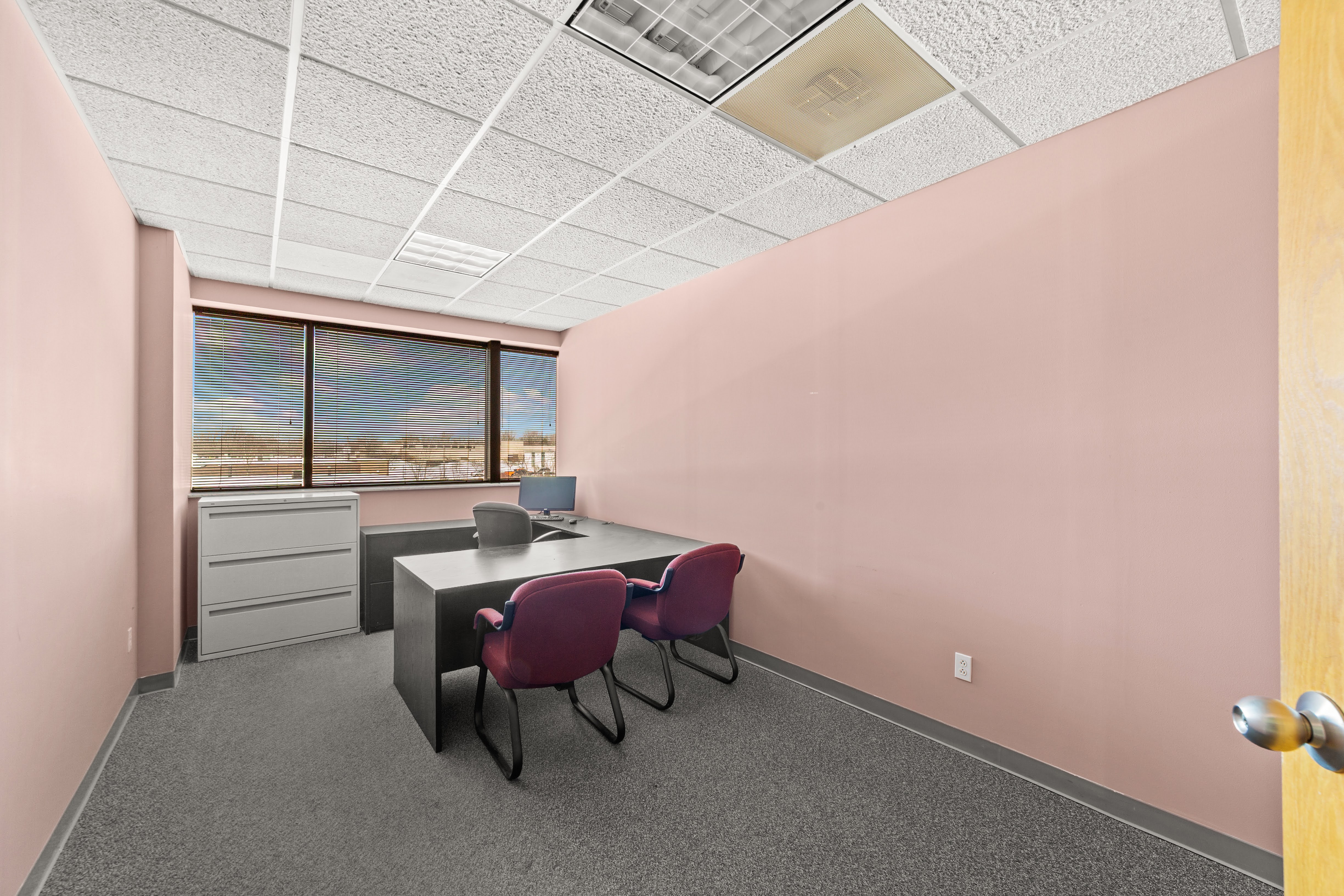 Empty office with desk, monitor, and chairs