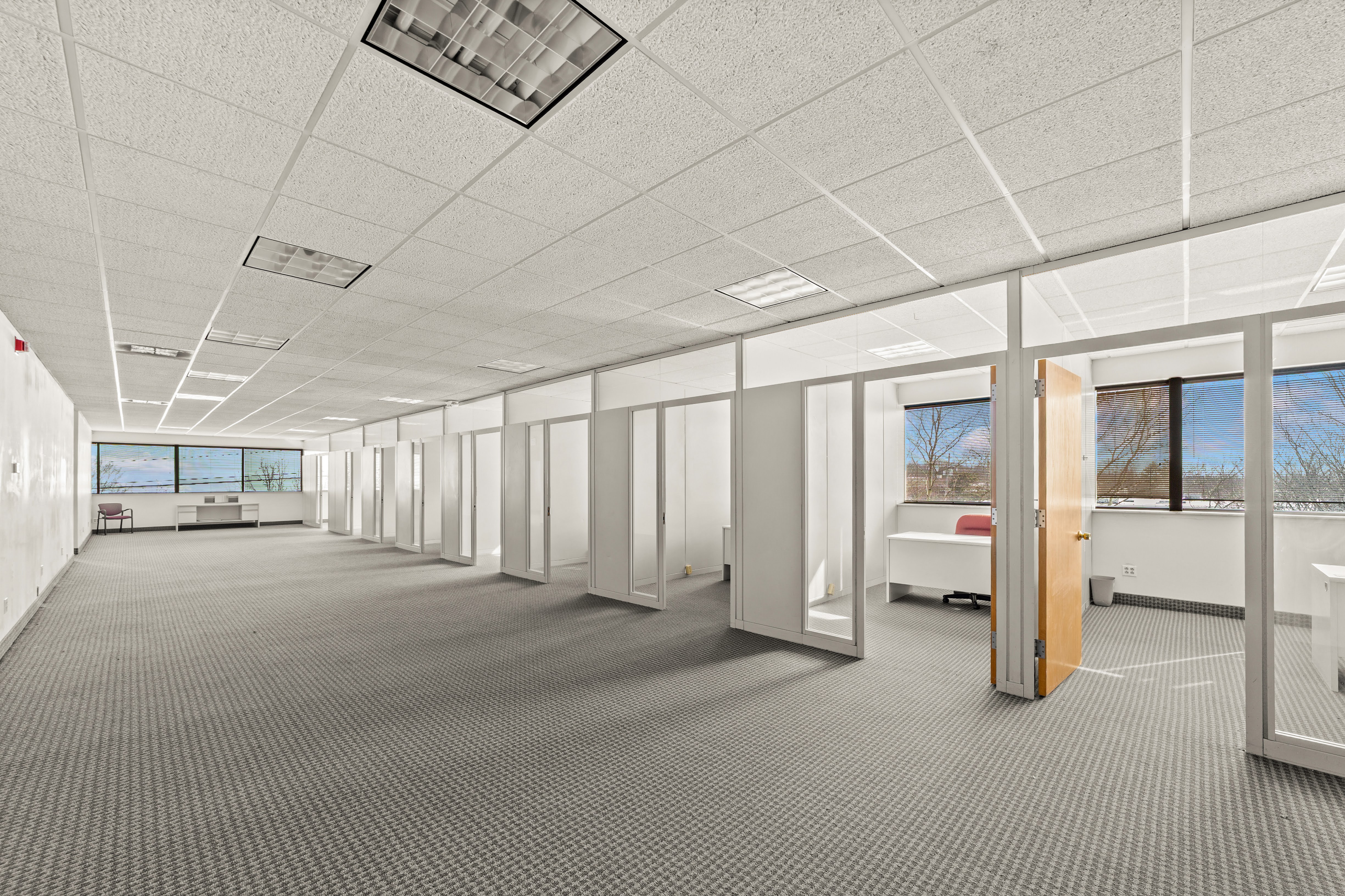 Large empty office space with glass-fronted offices