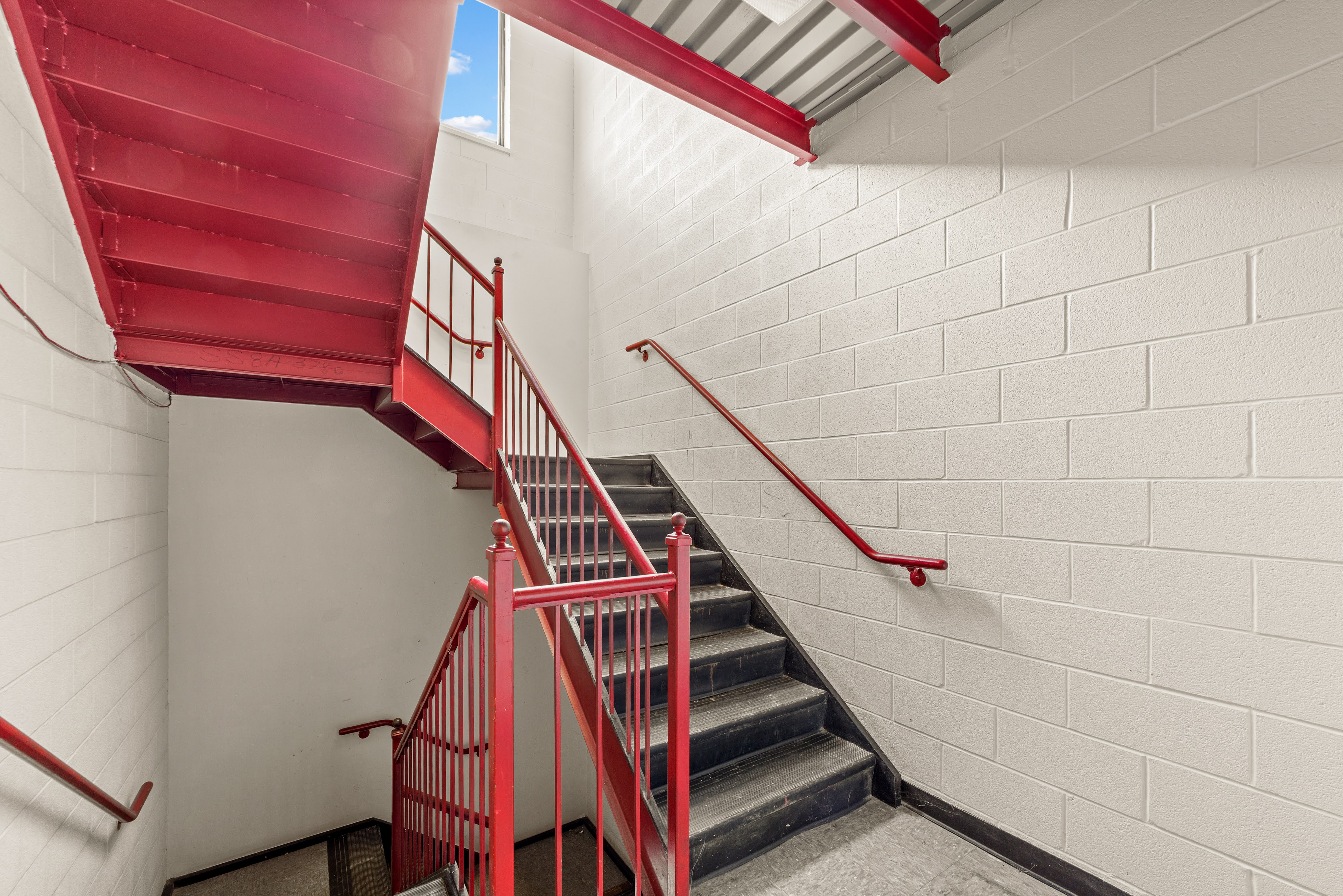 Red metal staircase between cinder block walls