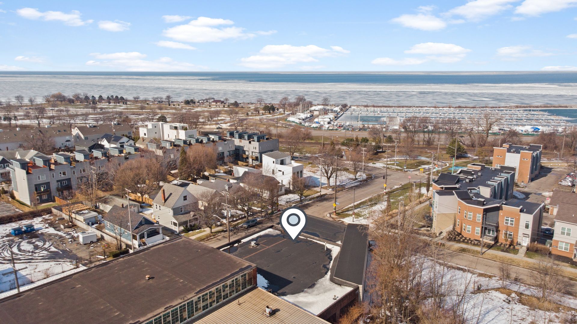 Aerial view of a residential area near a frozen body of water, with a location pin marking a building.