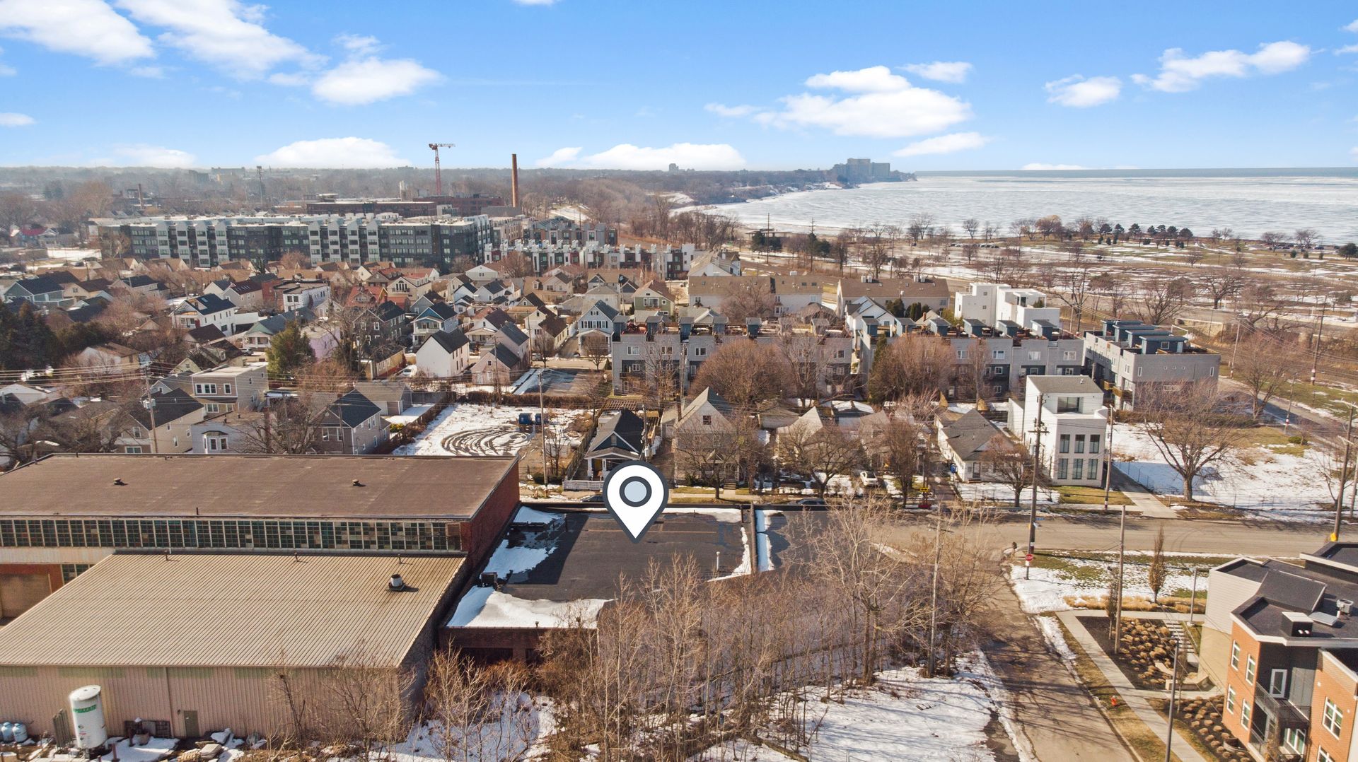 Aerial view of a residential neighborhood near a large body of water, with a location pin highlighting a specific property.
