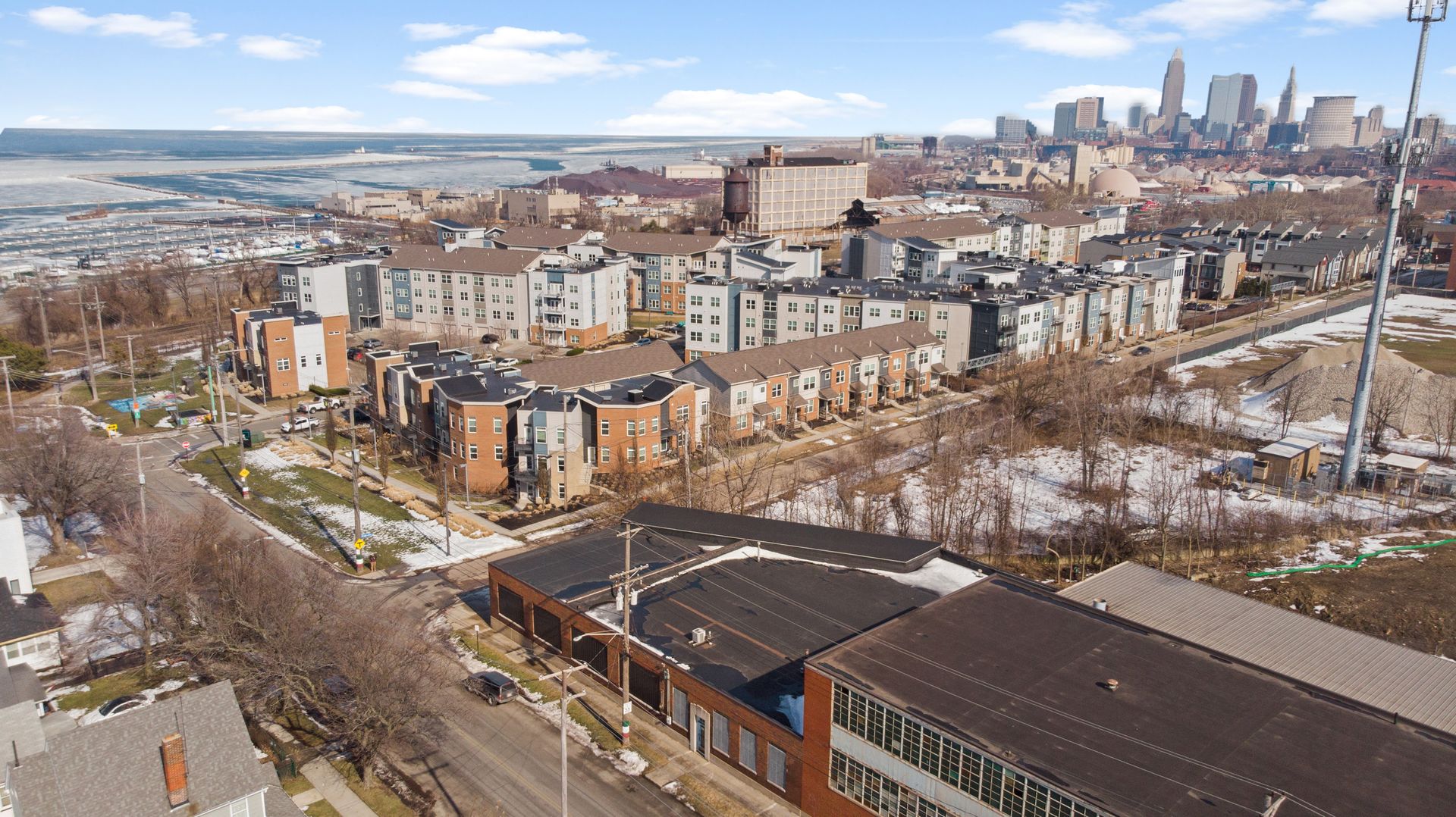 Aerial view of a residential neighborhood with modern townhouses and city skyscrapers in the background.