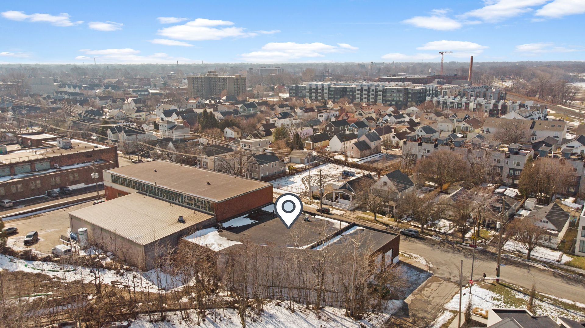 Aerial view of a suburban neighborhood with a mixture of residential houses and industrial buildings, marked by a location pin.