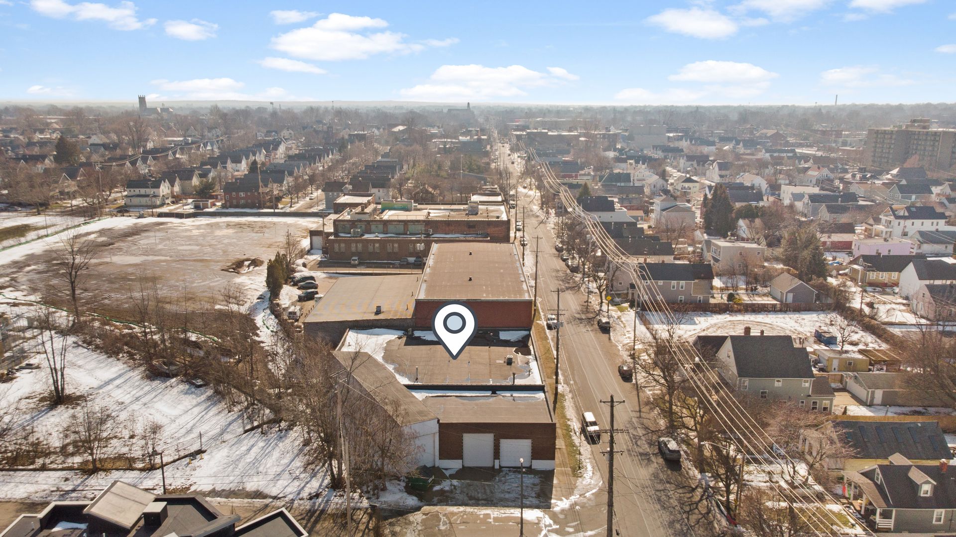 Aerial view of a snow-dusted suburban neighborhood with a building marked by a location pin.