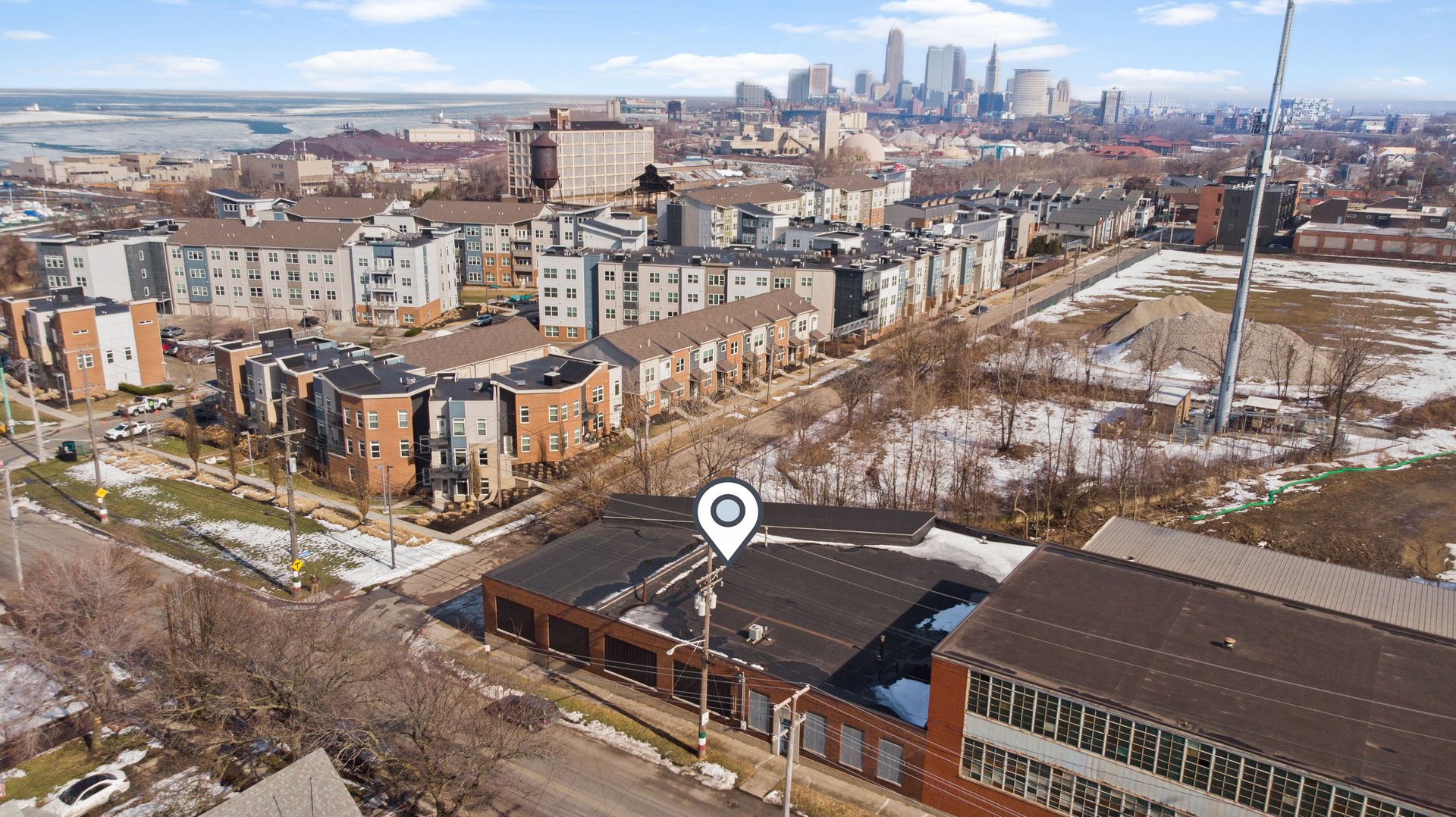 Aerial view of a residential neighborhood with modern buildings and a location marker icon.